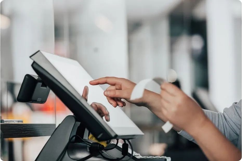 Pessoa utilizando sistema de PDV touchscreen enquanto segura um comprovante, representando a praticidade e modernização que um sistema para cafeterias proporciona.