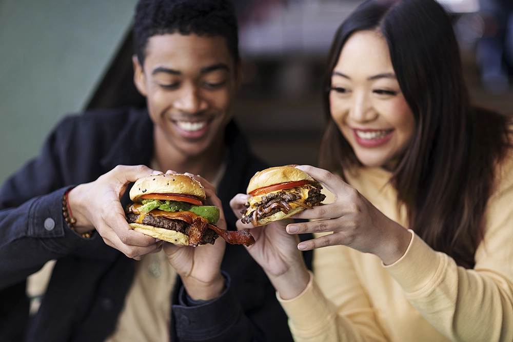 Um homem e uma mulher sorrindo segurando hamburgueres