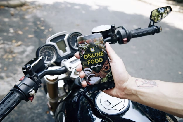 mão de um homem sentado em cima de uma motocicleta segurando um celular