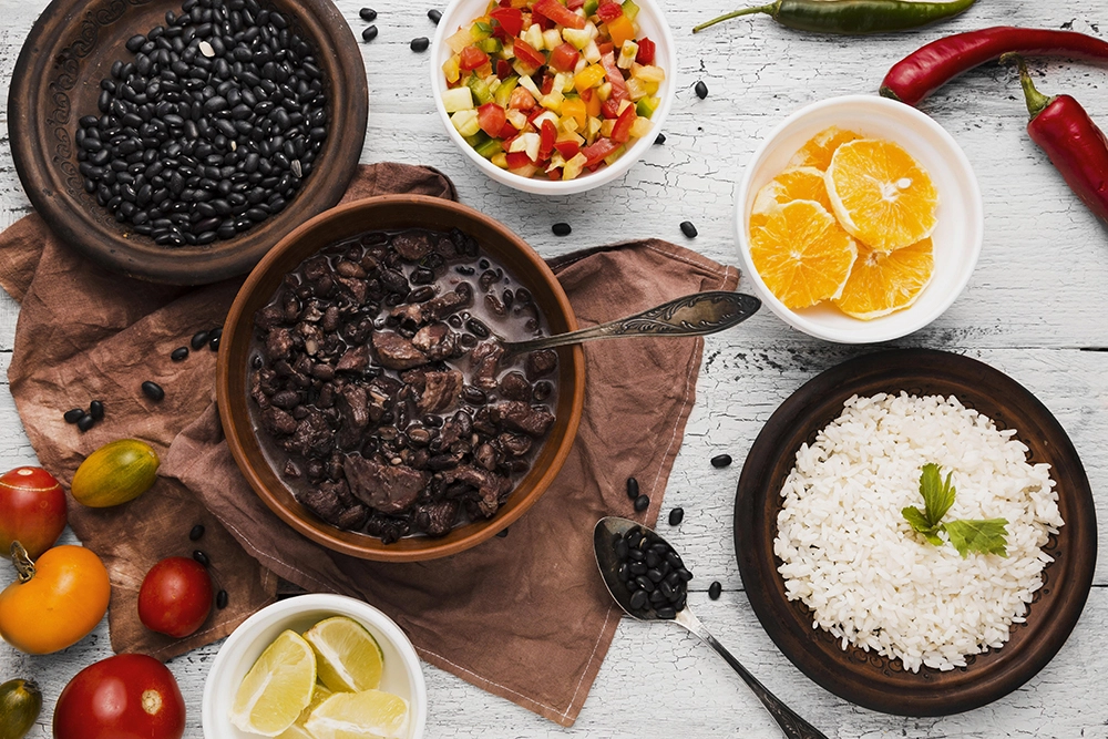 uma mesa branca com panelas de comida acompanhado de limao e saladas