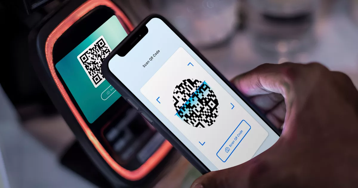 Mão segurando celular com câmera aberta escaneando QR code exibido em terminal de pagamento com iluminação laranja ao redor, pagamento por Pix no restaurante