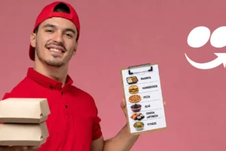 Entregador de uniforme vermelho segurando caixas de delivery empilhadas e prancheta com cardápio ilustrado de marmita, hambúrguer, pizza, açaí, comida japonesa e fitness
