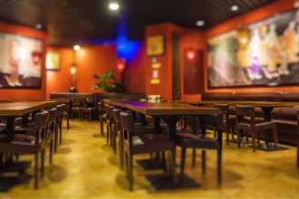Salão de lanchonete com mesas e cadeiras de madeira, paredes coloridas e quadros decorativos, mostrando o ambiente de um estabelecimento de food service antes de abrir para o público