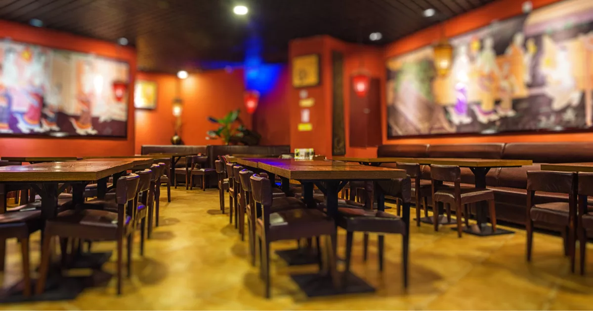 Salão de lanchonete com mesas e cadeiras de madeira, paredes coloridas e quadros decorativos, mostrando o ambiente de um estabelecimento de food service antes de abrir para o público