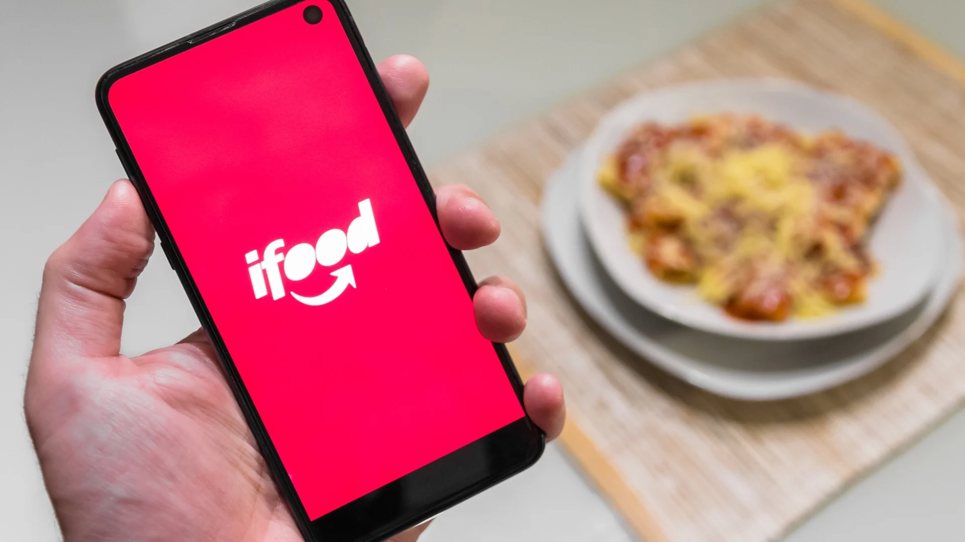 pessoa segurando um celular na mão com aplicativo ifood aberto