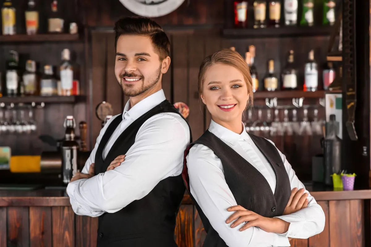 Dois vendedores sorridentes em restaurante, simbolizando confiança e profissionalismo. Inspiração para homenagear a equipe de vendas no Dia do Vendedor com frases motivacionais