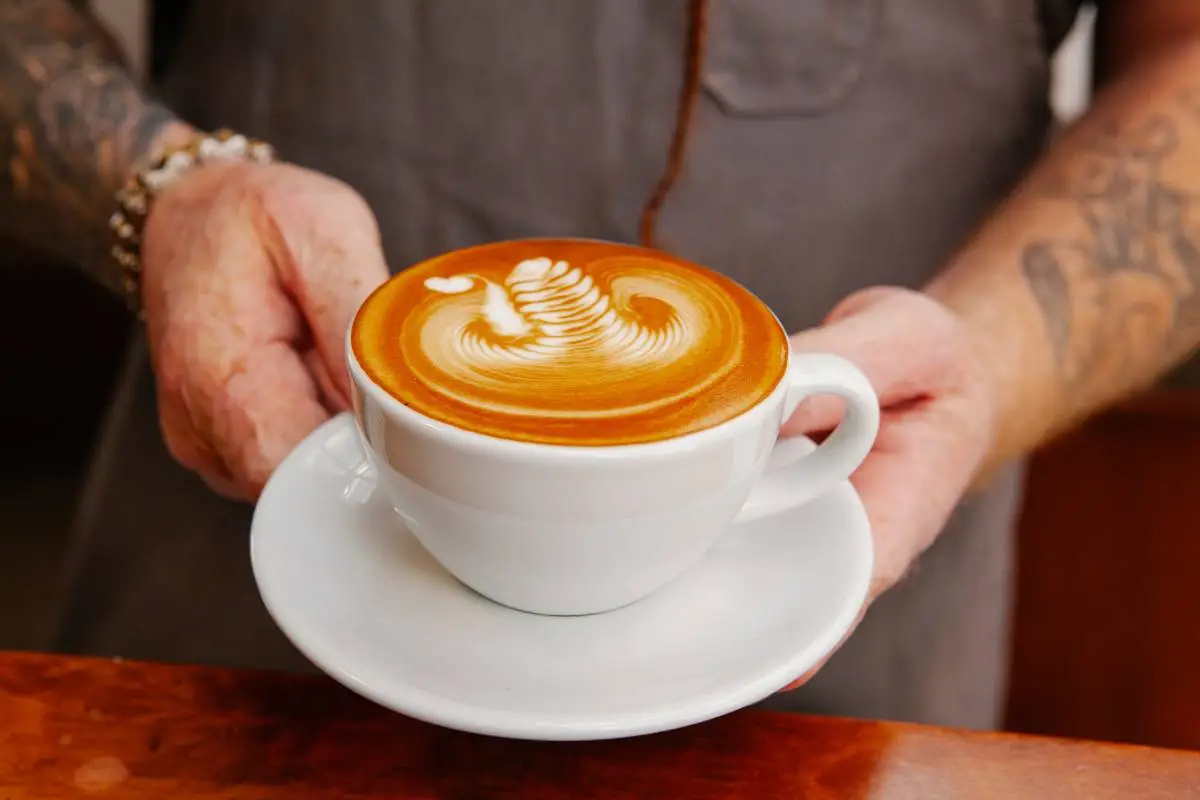 Xícara de café com latte art em forma de coração, servida em uma cafeteria, simbolizando a atenção aos detalhes e a qualidade do produto