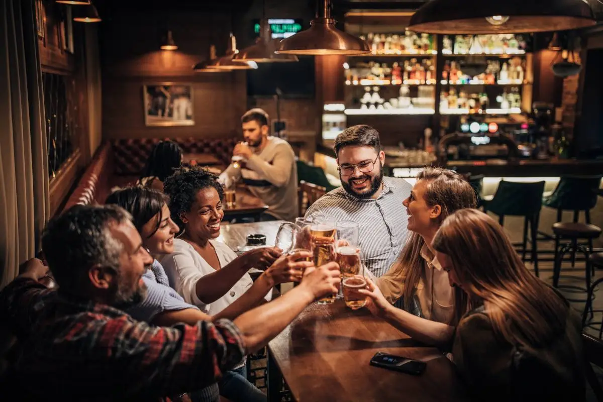 Grupo de amigos brindando com cerveja em um bar, representando um ambiente festivo e ideal para confraternizações