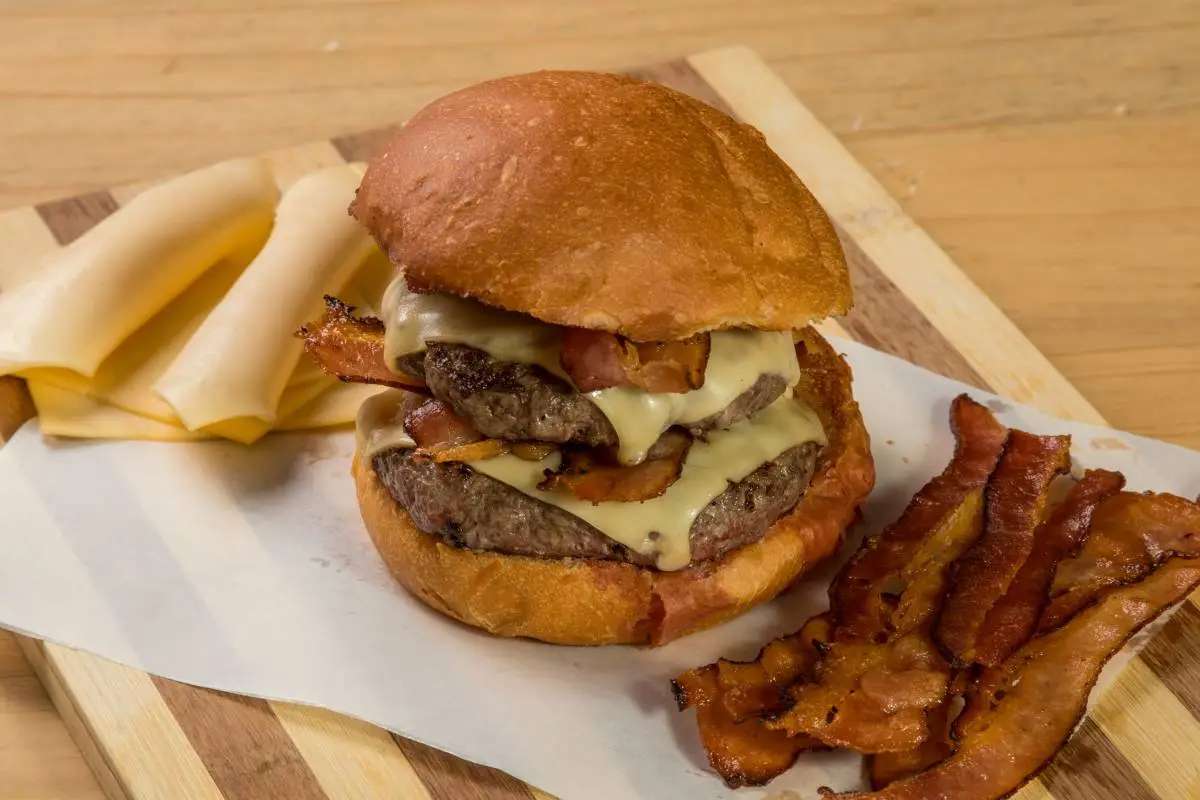 Hambúrguer artesanal com bacon e queijo derretido em pão macio.