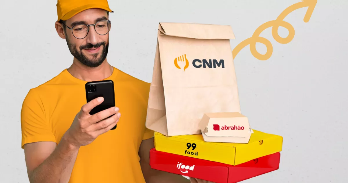Entregador de boné e camiseta amarela conferindo pedido no celular, segurando caixas empilhadas com logos do CNM, Abrahão, 99Food e iFood