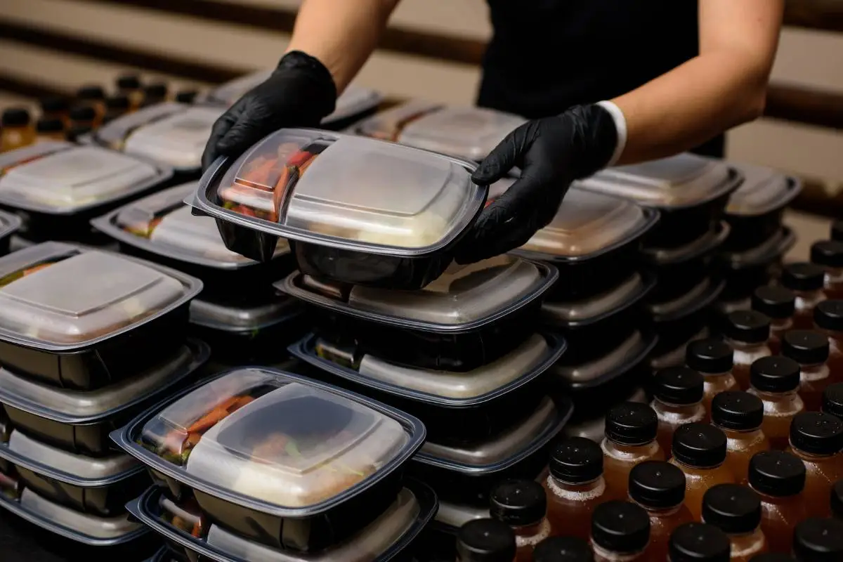 Refeições fitness congeladas sendo embaladas em recipientes plásticos.