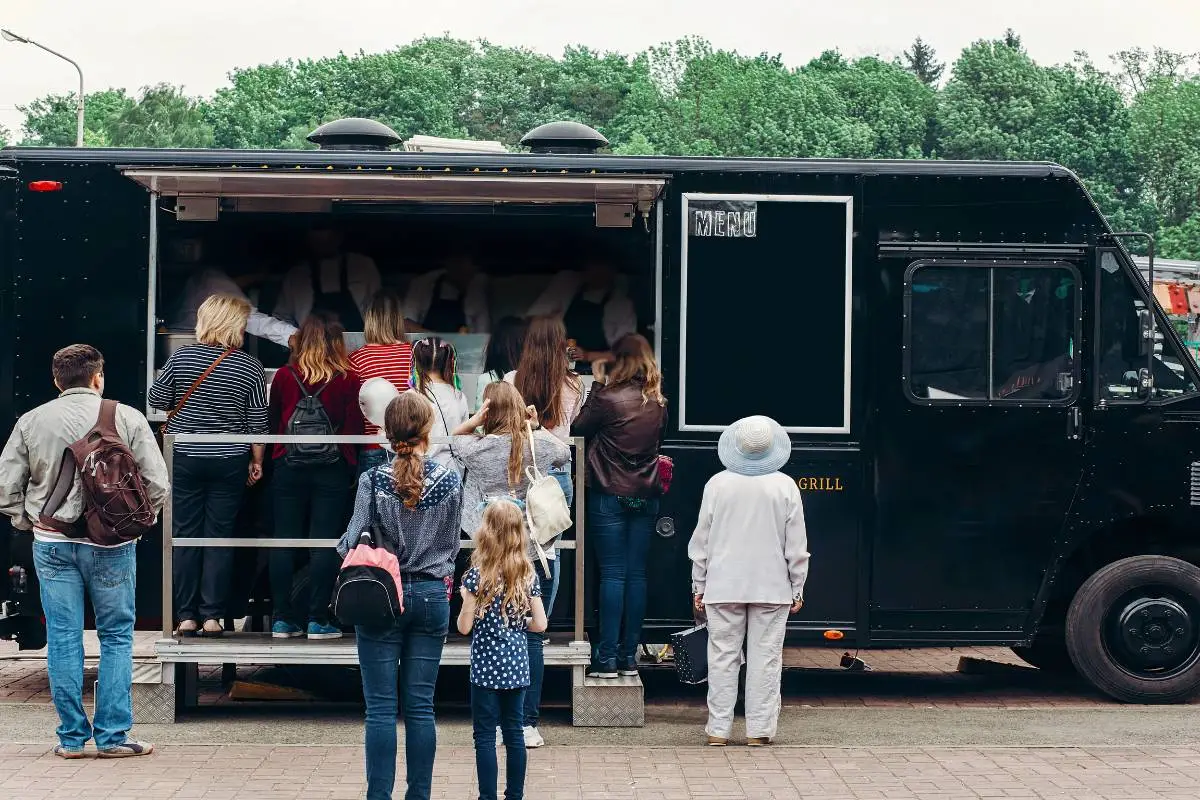 Clientes esperando para serem atendidos em um food truck de hamburgueria com design moderno.