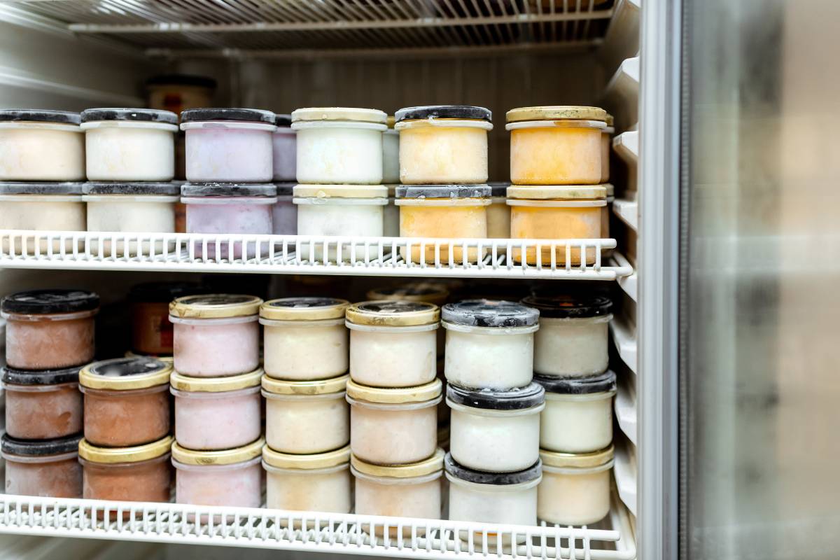Embalagens de alimentos congelados organizadas em prateleiras de freezer industrial, exemplificando boa gestão de produtos com alta rotatividade em restaurantes.