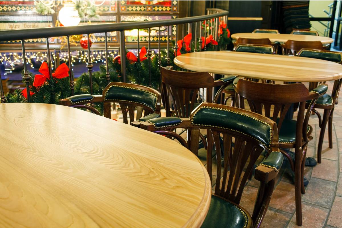 Espaço interno de restaurante decorado para o Natal, com guirlandas verdes e laços vermelhos ao longo das grades, criando uma atmosfera festiva e acolhedora.