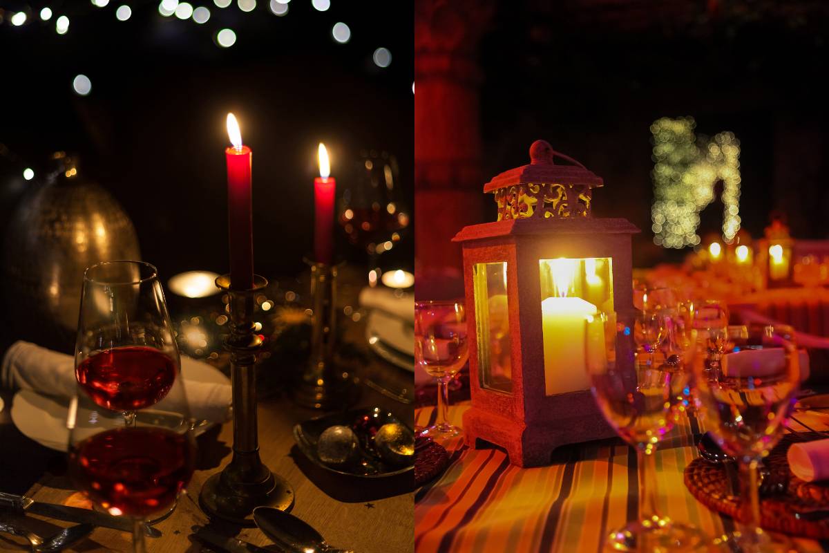 Mesa decorada para o Natal com taças de vinho, candelabros e uma lanterna, criando um clima romântico e aconchegante para a temporada de festas.