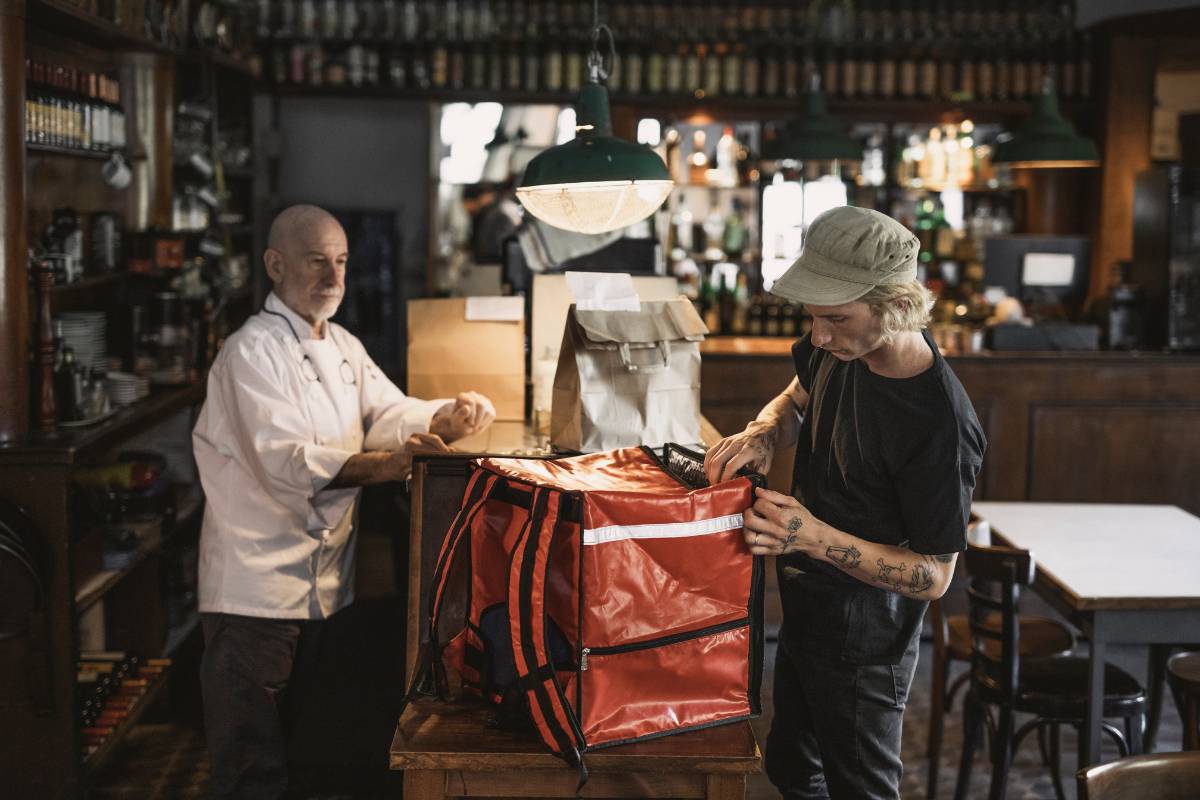 Funcionário de restaurante preparando pedidos para entrega em uma sacola de delivery