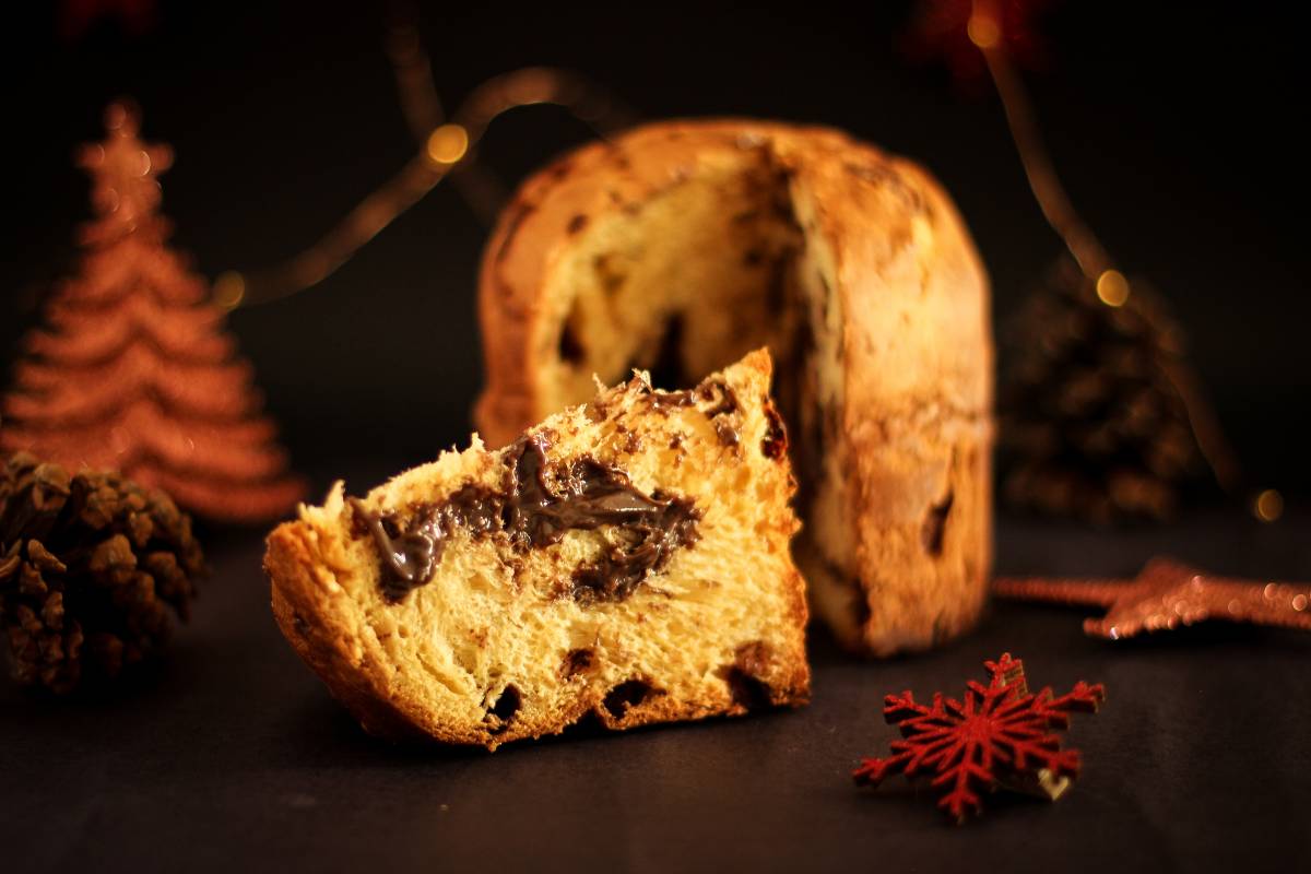 Panetone recheado com creme de chocolate, decorado com cenário natalino ao fundo.