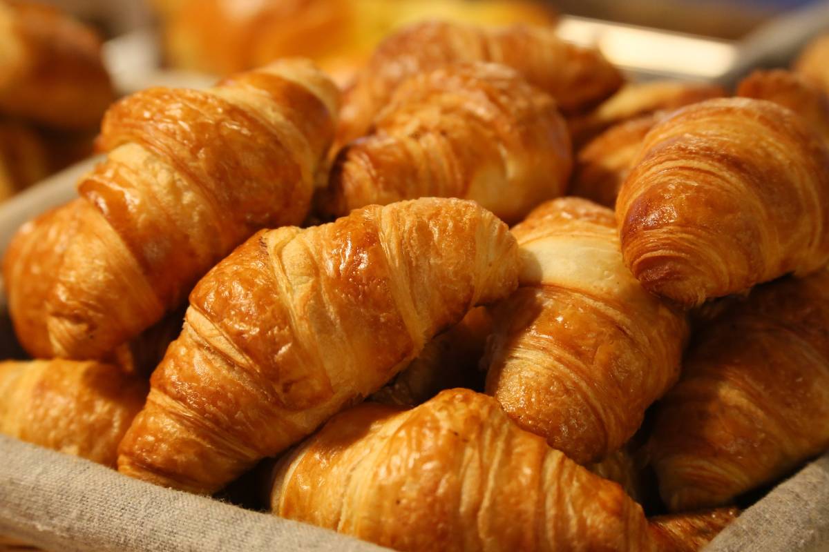 Cesto de croissants dourados e frescos, prontos para servir em uma cafeteria