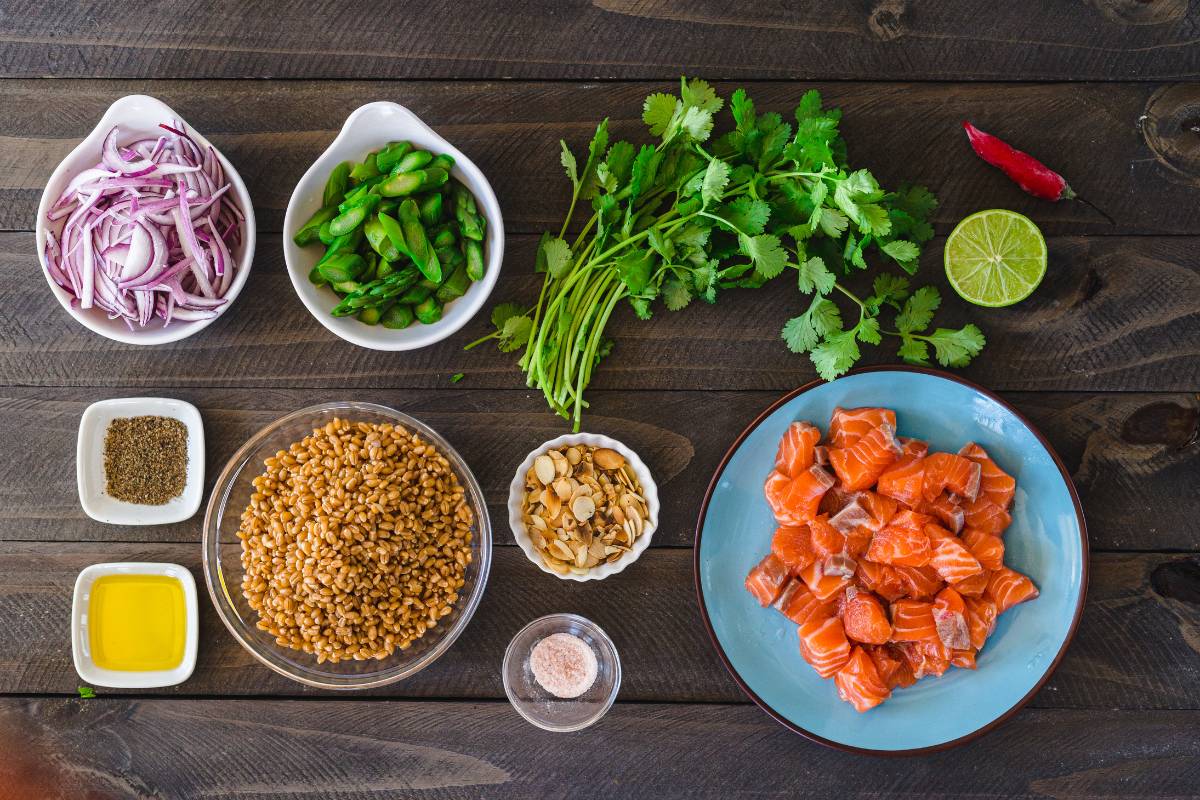 Ingredientes organizados em tigelas e pratos, incluindo salmão, vegetais e temperos, exemplificando o Mise en Place antes do preparo