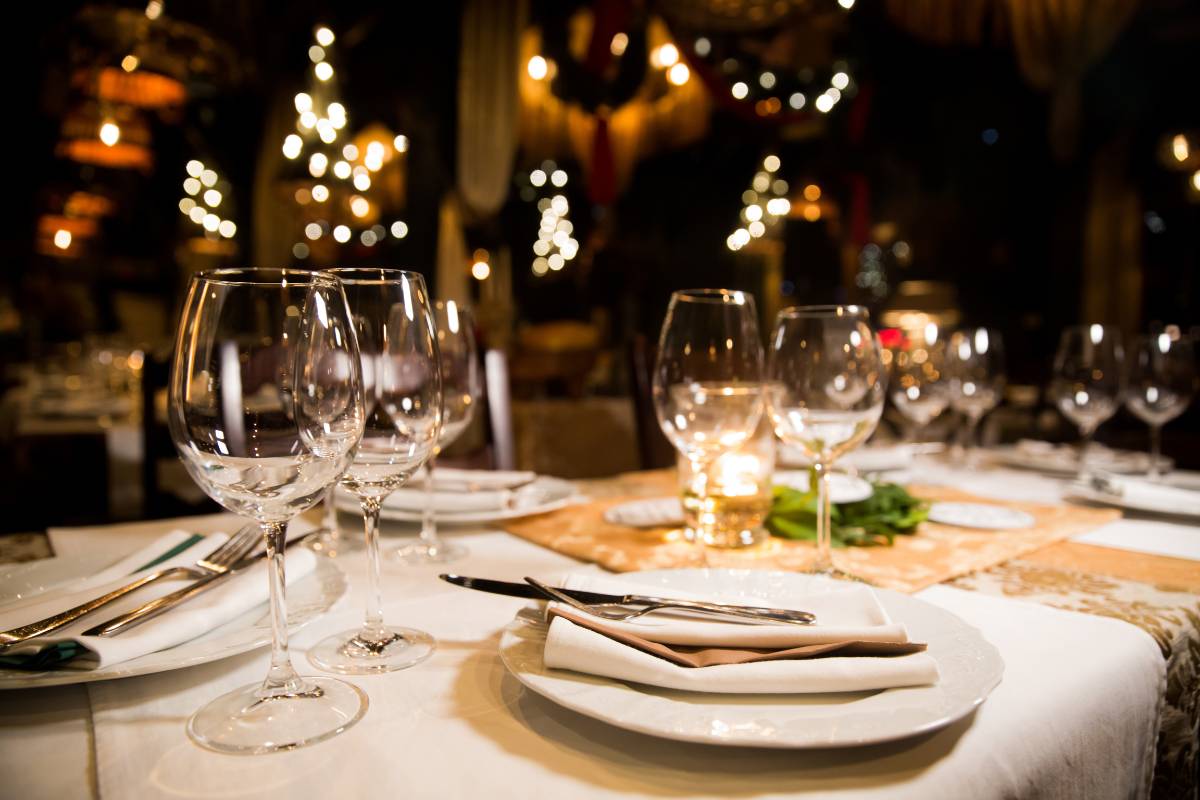 Mesa de restaurante elegantemente preparada com taças de vinho e talheres organizados, destacando o conceito de Mise en Place no salão