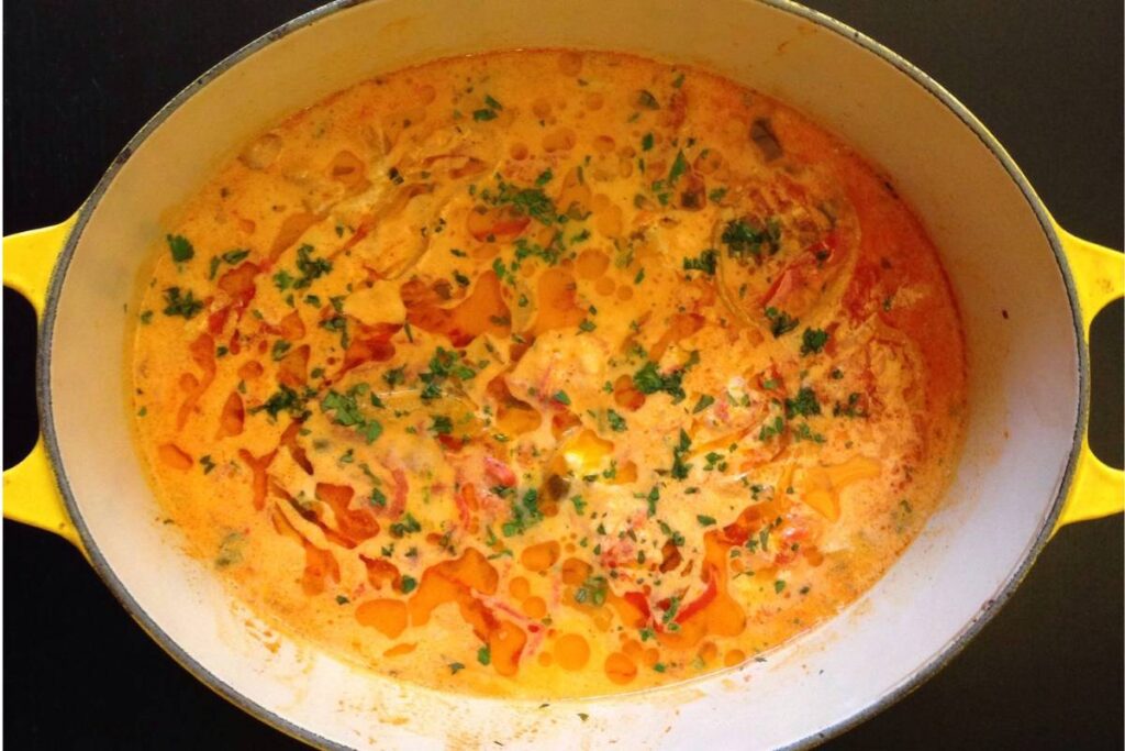 Moqueca baiana com leite de coco e azeite de dendê - Prato típico feito com peixe cozido em leite de coco, azeite de dendê e temperos, servido em panela de ferro amarela.