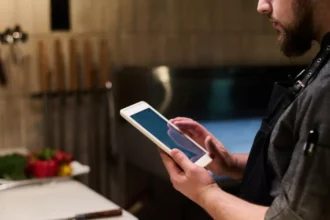 Profissional de cozinha usando tablet para acompanhar pedidos em um sistema PDV para delivery dentro do restaurante.