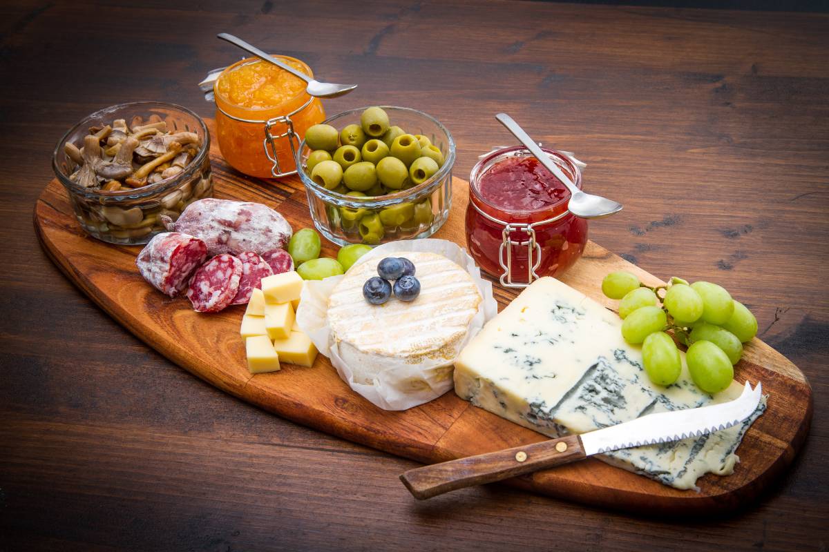 Tábua de frios com queijos e embutidos: Tábua rústica com seleção de queijos, embutidos, azeitonas, geléias e frutas low carb como uvas e mirtilos.