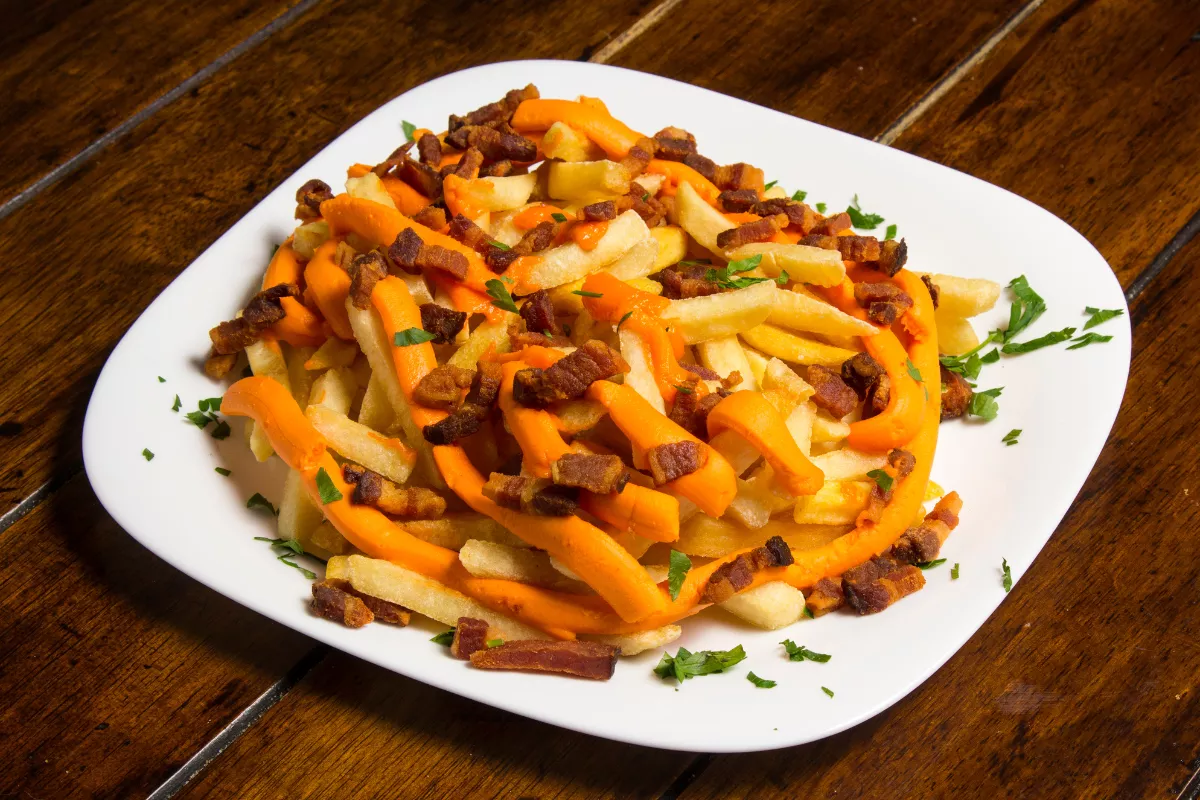 Batata frita com cheddar e bacon: Prato de batatas fritas crocantes, cobertas com cheddar cremoso e pedaços crocantes de bacon.
