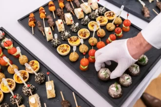 Bandejas organizadas com diferentes tipos de finger foods, como mini quiches, espetinhos e canapés, prontas para servir em eventos e coquetéis.