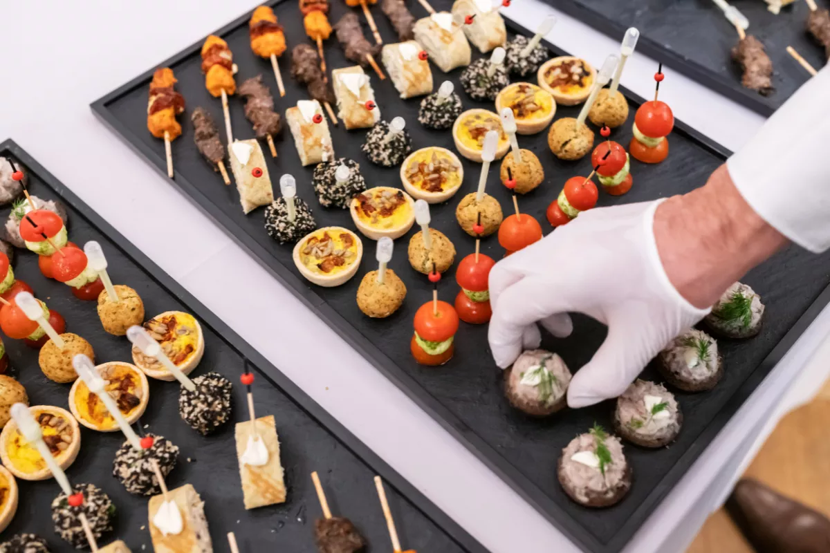 Bandejas organizadas com diferentes tipos de finger foods, como mini quiches, espetinhos e canapés, prontas para servir em eventos e coquetéis.