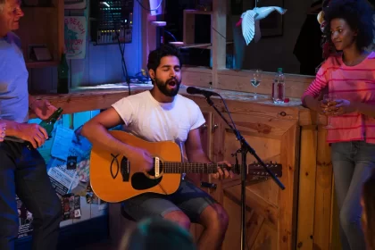 Cantor tocando violão e cantando ao vivo em barzinho aconchegante, com público próximo e ambiente informal — perfeito para uma playlist de música para barzinho.