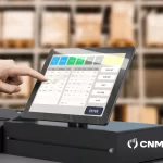 Pessoa utilizando sistema PDV em tela touch integrada ao caixa de um restaurante, com interface moderna e logo do CNM visível, representando automação no ponto de venda.