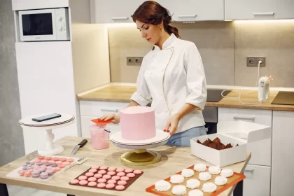 Empreendedora confeiteira finalizando decoração de bolo com topo personalizado, simbolizando a importância da gestão e cuidado nos detalhes desde o início do negócio.