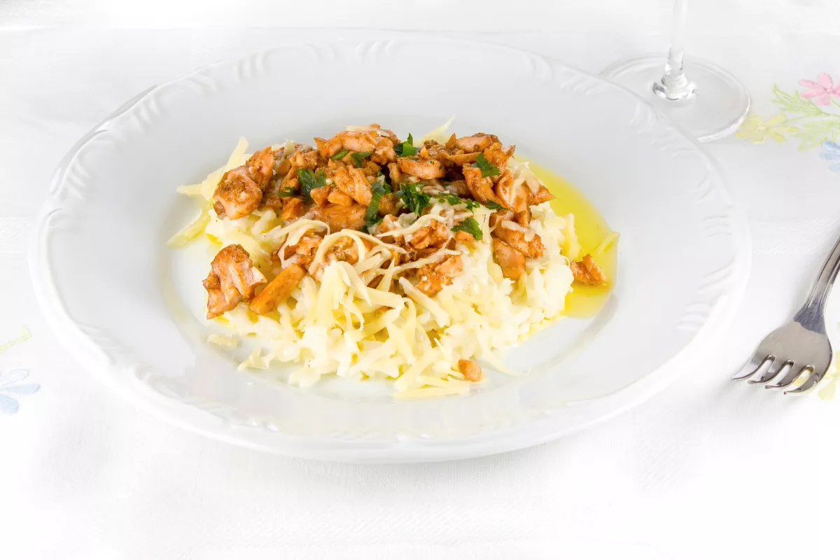 Prato de salmão grelhado servido sobre um cremoso risoto de parmesão, decorado com salsa fresca, ideal como opção premium para cardápios especiais de Dia das Mães.