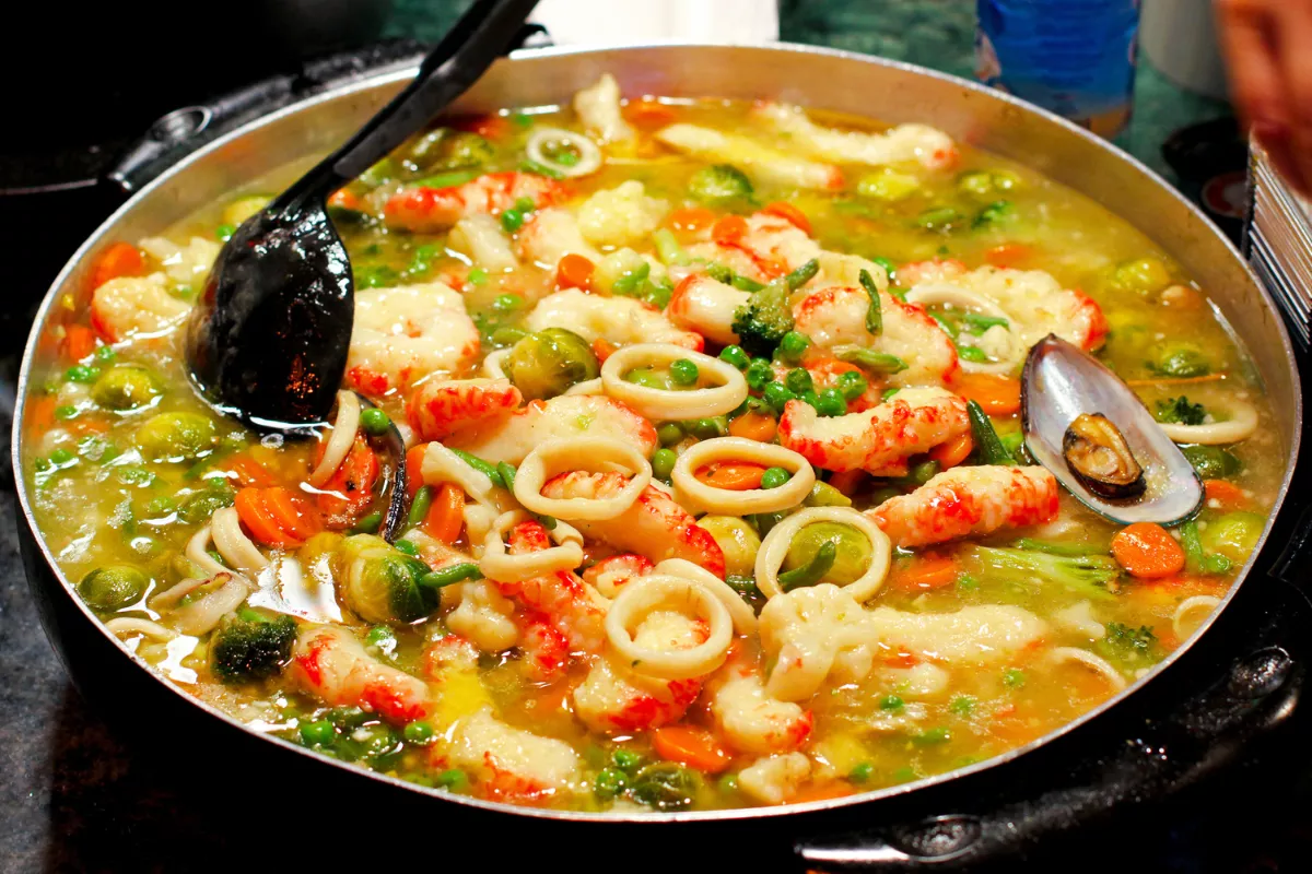 Moqueca de camarão com caldo encorpado, legumes coloridos e frutos do mar, servida em panela grande, excelente escolha de prato principal para encantar no almoço de Dia das Mães.
