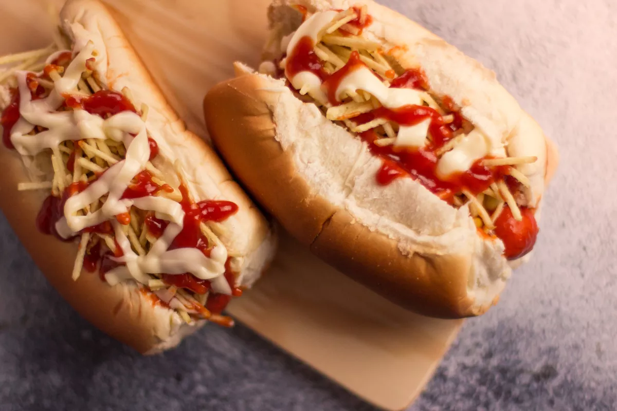 Cachorro-quente tradicional com salsicha, batata palha, ketchup e maionese, servido em pão macio, pronto para servir na barraca junina.