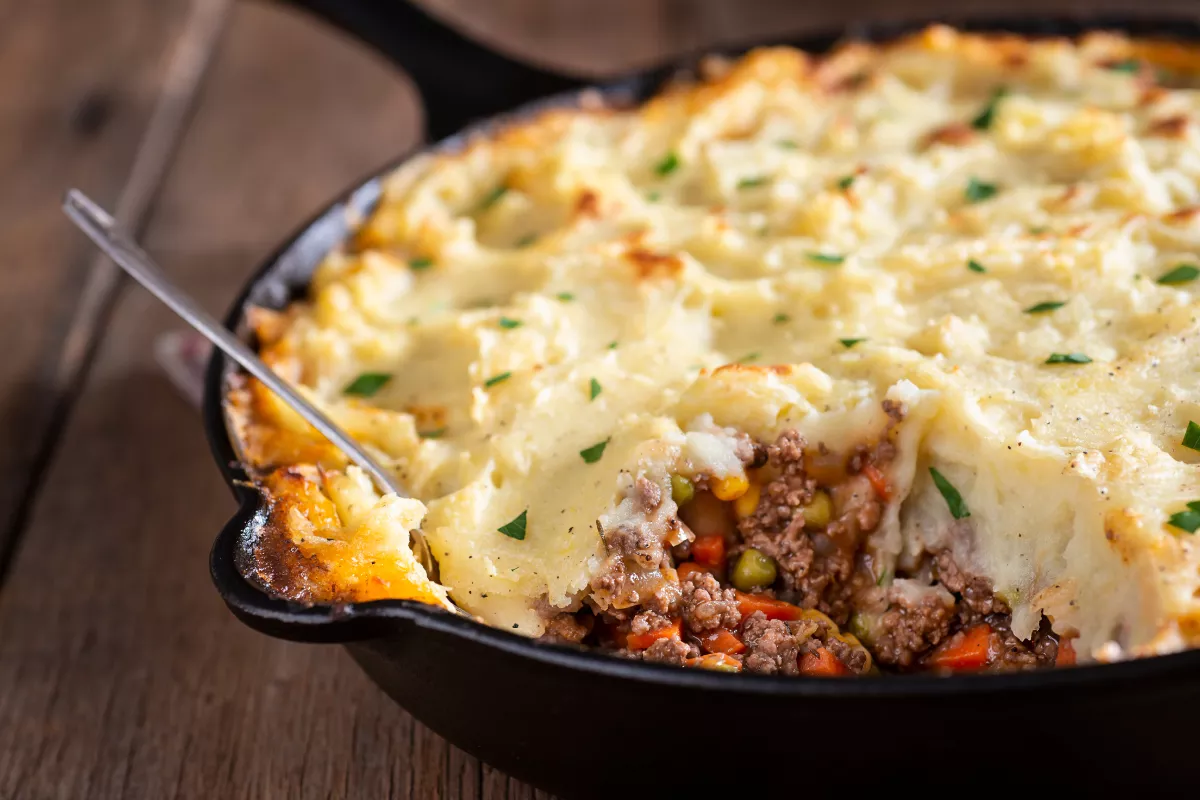 Escondidinho gratinado com purê de batata e recheio de carne moída com legumes, servido em frigideira rústica, prato caseiro que aquece no inverno.