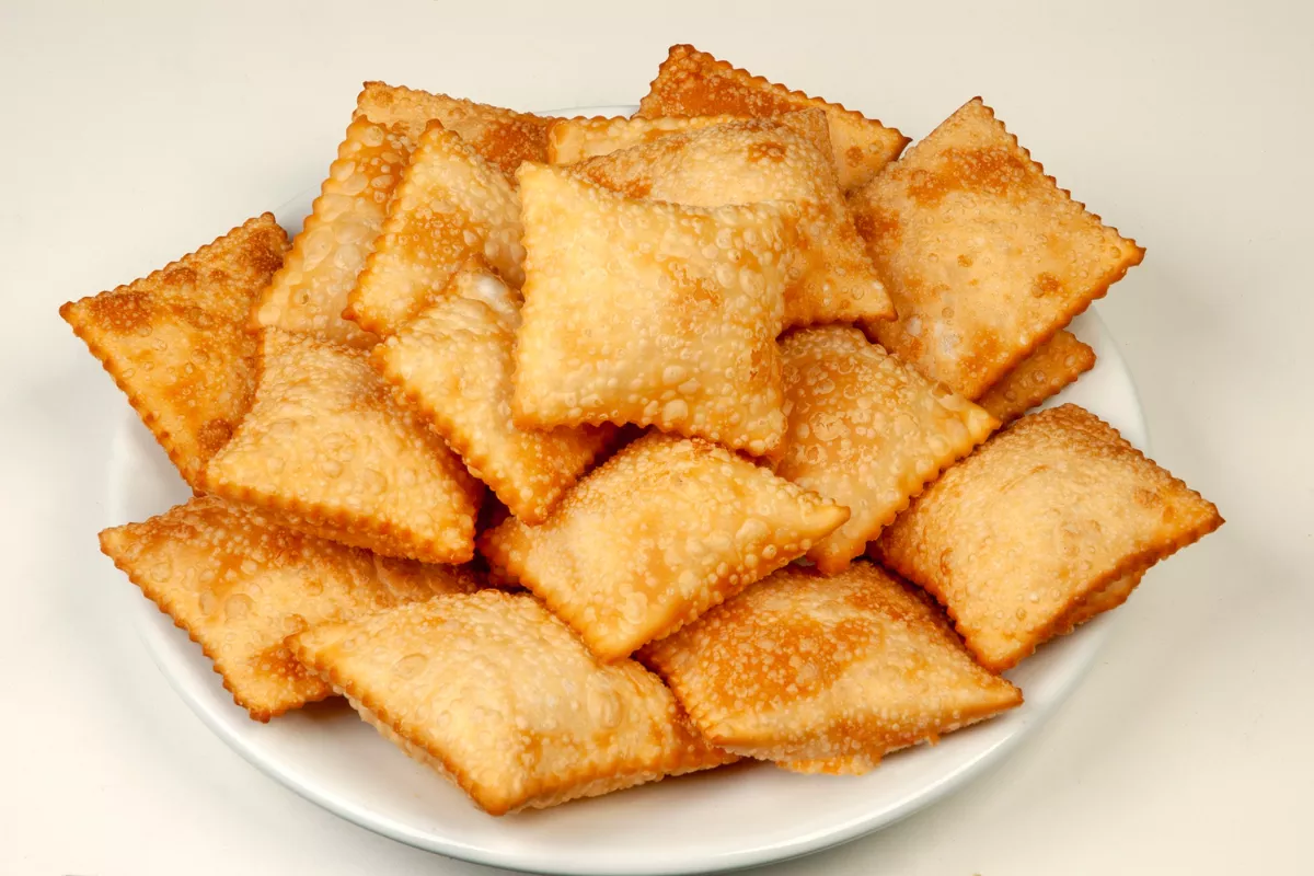 Prato branco cheio de mini pastéis dourados e bem fritos, ilustrando variedade de produtos vendidos em pastelarias que buscam agilidade e controle.