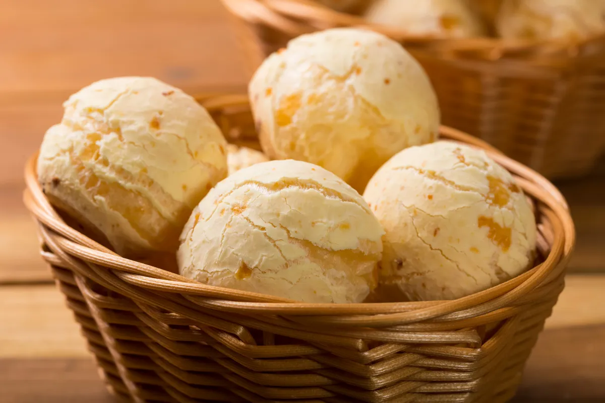 Cesta com pães de queijo dourados e crocantes, em close, simbolizando o Dia do Pão de Queijo e ideias de pratos criativos para padarias, lanchonetes e cafés.