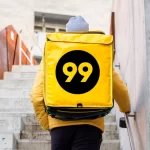 Entregador com mochila da 99 sobe escada em área urbana, simbolizando o retorno da 99Food ao delivery com proposta de taxa zero para restaurantes.