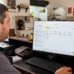Dono de restaurante usando o PDV ControleNaMão em um computador no balcão do estabelecimento.