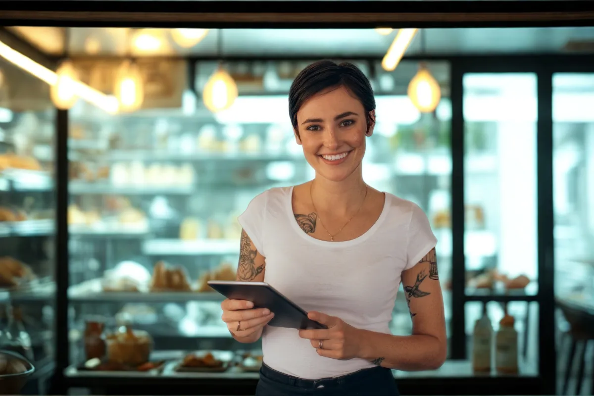Gestora de restaurante self-service usando tablet para controlar a operação, simbolizando o uso de sistema de gestão como o CNM para aumentar o lucro.