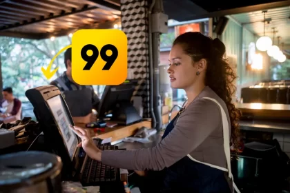 Atendente de restaurante usando sistema PDV em frente de caixa, com destaque para o ícone da 99Food, simbolizando integração entre o sistema e a plataforma de delivery.
