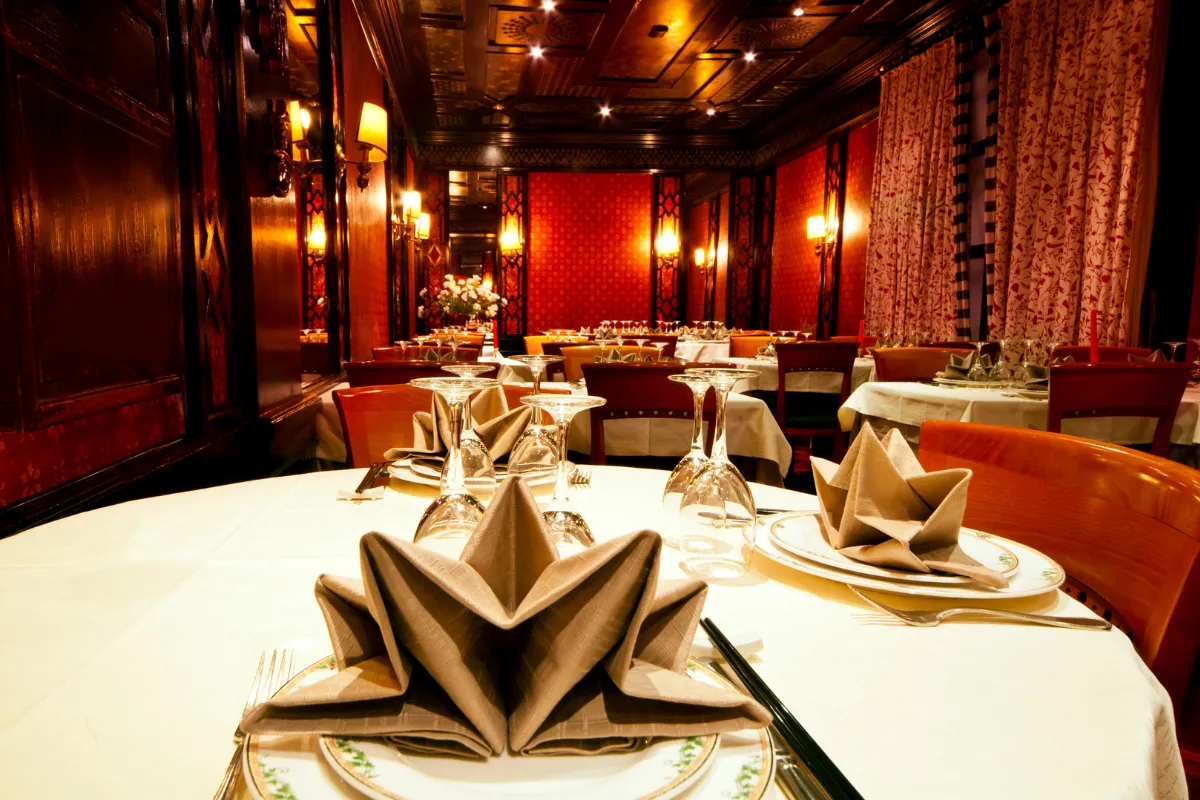 Ambiente sofisticado de restaurante de luxo, com mesas finamente postas e decoração elegante, ilustrando um modelo de alto custo na comparação entre tipos de restaurante.