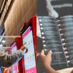 Homem usando totem de autoatendimento digital ao lado de cardápio ilustrado com fotos, destacando opções modernas e interativas.