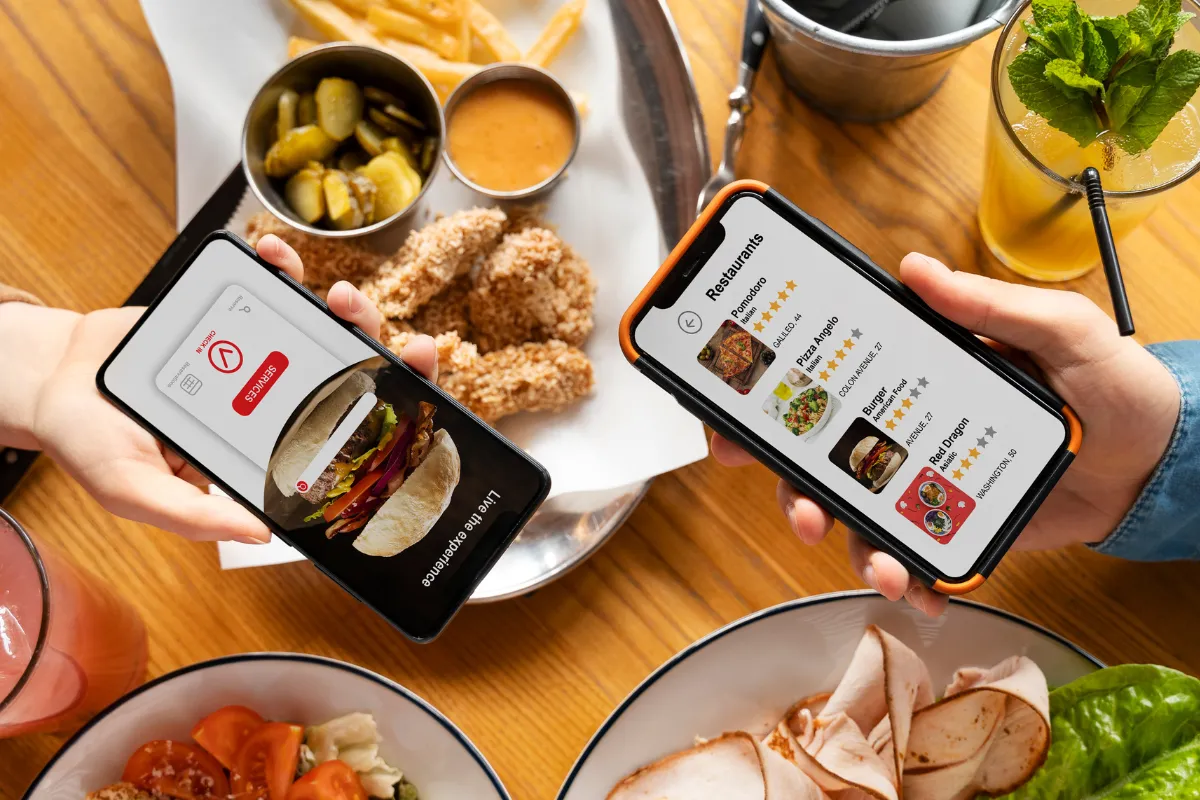 Duas pessoas segurando smartphones com cardápios digitais abertos, representando pedidos rápidos via QR Code ou link próprio diretamente do celular.