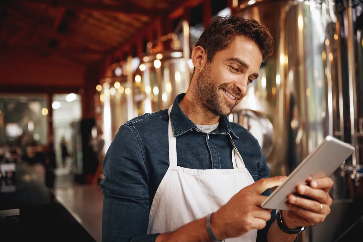 Garçom utilizando tablet para registrar pedidos em um ambiente de restaurante, destacando o uso de comandas eletrônicas para agilidade e integração com cozinha e caixa.