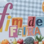 Arte da “Newsletter CNM Fim de Feira – Edição 3” com fundo de toalha xadrez azul, colagem de letras coloridas formando o título, megafone roxo à esquerda e frutas, legumes e verduras na parte inferior, com efeito de neve