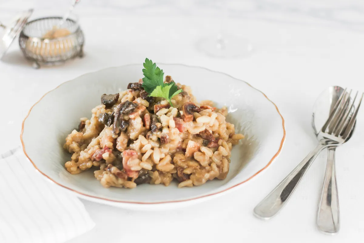 Risoto de cogumelos servido em prato fundo com salsa fresca, opção vegetariana criativa e sofisticada para ampliar o alcance do cardápio comemorativo.