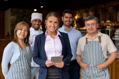Equipe de restaurante composta por gerente, cozinheiros e atendentes posando para foto, mostrando os cargos essenciais para uma operação equilibrada.